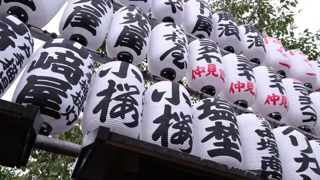 Traditional Japanese Chochin Paper Lanterns with calligraphy hanging in rows at a shrine in Japan