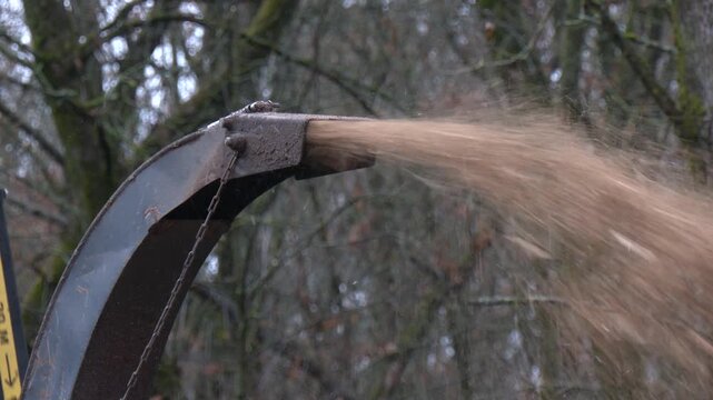 Leaf Shredder on Axle in Action. Mobile wood and branch shredder in the city park. Agricultural machinery, wood chipping machine. Machinery wood shredder the chipper at work for tree branches
