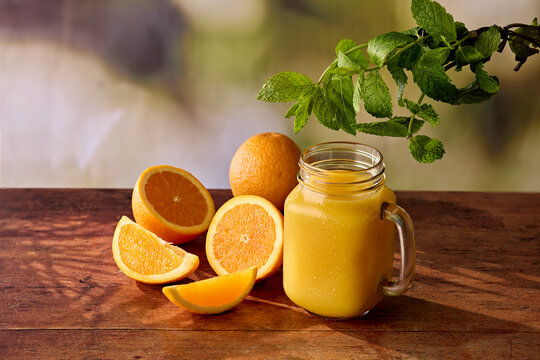 Fresh Orange Juice in Jam Jar Glass with Oranges and Mint on Dark Wooden Surface
