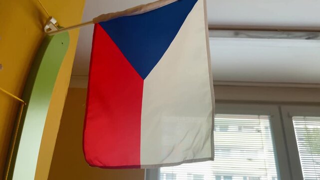 Czech flags inside a kindergarten. The flags are placed on a wall, mounted indoors as part of the preschool environment. National symbols in public space. Taken on mobile device