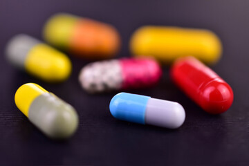 Various capsules on a black background. Selective focus. Medicines.
