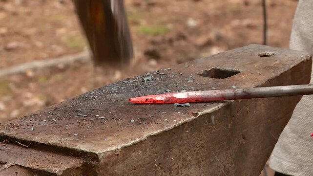 a blacksmith forges a metal product on an anvil