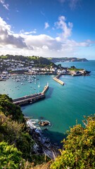 Fototapeta premium Scenic coastal harbor view with turquoise water, breakwater, and hillside town