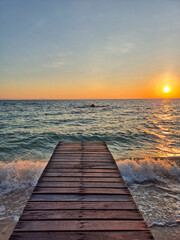 Fototapeta premium Glistening sunset over the ocean from a wooden pier in Klaeng, Rayong, Thailand