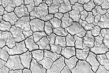 Top view of dry cracked earth ground texture background in black and white,High angle view of extreme drought conditions showing parched, cracked soil surface. A monochrome abstract texture.