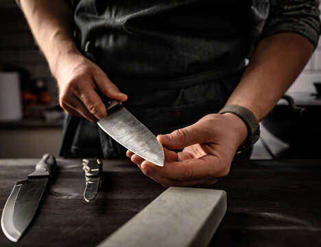 Man cheking a knife after using sharpen stone tool. Master sharpening knife on a grindstone