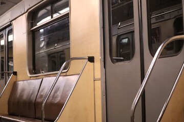 The interior of an empty Kyiv metro train car features brown seats, light walls, and chrome handrails. This image is suitable for themes of urban transport © ForStock