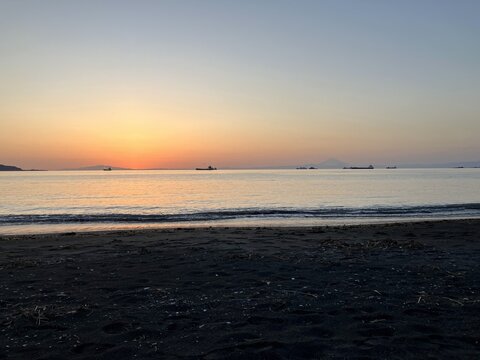 The afterglow of a sunset over the dark sandy beach of Tateyama with Mount Fuji on the distant horizon
