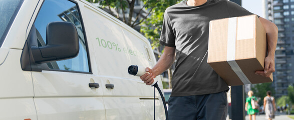 Driver with charging plug next to of electric van © scharfsinn86