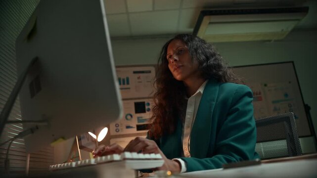 Determined african american female professional typing on a computer keyboard while working overtime to meet a crucial business deadline