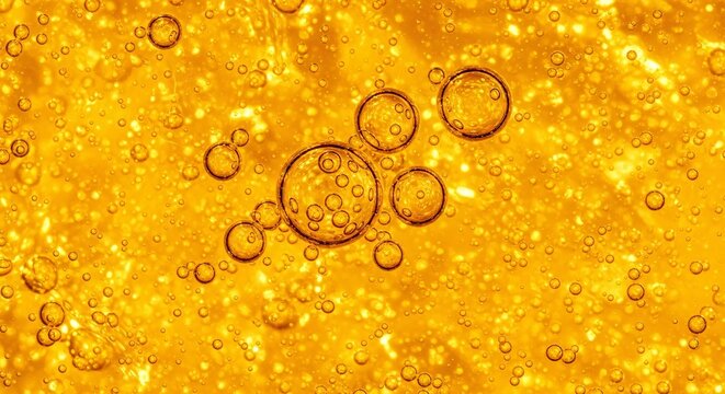 Vibrant amber texture background, macro detail of glowing golden essential oil or vitamin c serum droplets.
