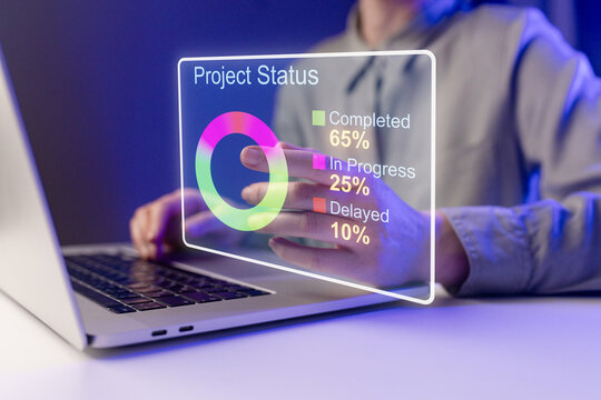 Person shows project status on laptop screen with data displayed in colorful graphic in office setting during late evening hours