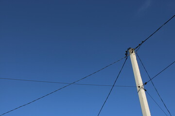 Power Lines Stretch Across a Blue Sky During the Day With a Clear View of the Utility Pole and Wires