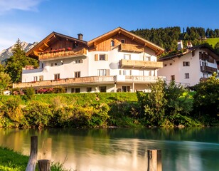 Obraz premium Scenic view of a European alpine lodge situated beside a river surrounded by greenery