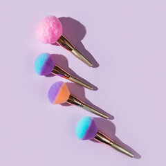 Colorful makeup brushes arranged on a light purple background for beauty application and cosmetic art