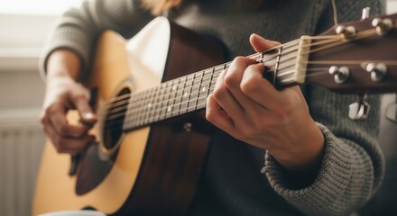 Close up of female hands playing acoustic guitar. Woman in sweater strumming chords on wooden musical instrument. Hobby, music lesson, creative lifestyle and acoustic performance concept.
