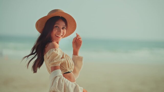 A joyful young Asian woman wearing a straw hat and a crop top, smiling brightly at the camera on a beautiful tropical beach during a sunny day, capturing the essence of freedom, summer vacation