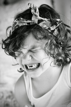Portrait of a happy girl wearing a headscarf squinting and pulling funny faces