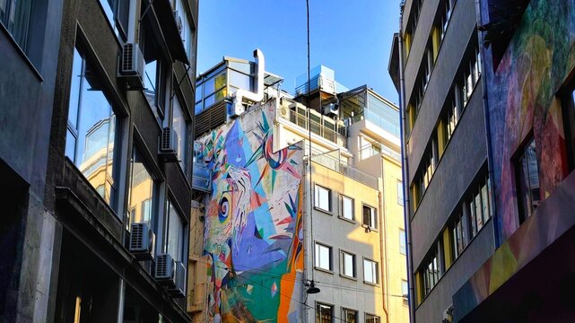 Photo of a colorful abstract street art mural on a building wall in a narrow street (Miaouli and Themidos) in the Psyrri neighborhood of Athens, Greece.