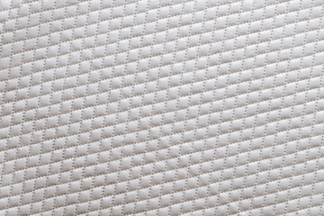 Fototapeta premium Quilted fabric with a diamond pattern used for bedding or upholstery in a home setting during daylight hours