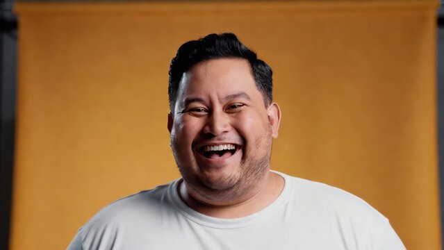 Smiling hispanic male adult against yellow background.