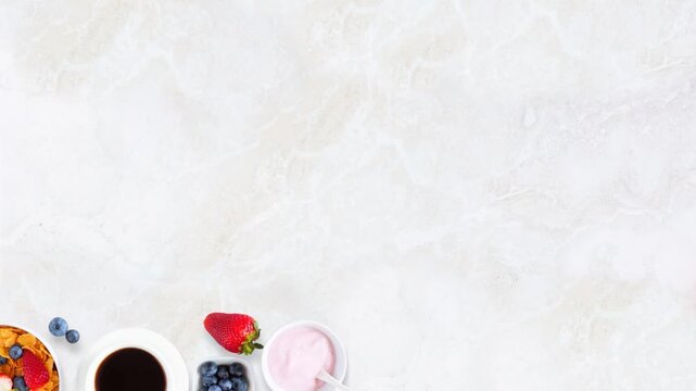 Breakfast food bottom border. Stop motion placement on a bright stone background with copy space. Fruits, cereal, waffles, yogurt, coffee and milk.