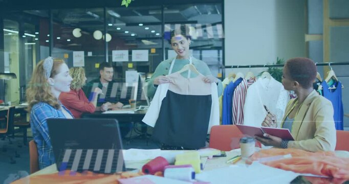 Presenter standing center initiating fashion review by lifting garment, rotating while team noting