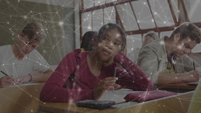 Female teenager pausing writing and daydreaming in classroom, translucent network overlay appearing