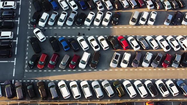 Top down aerial view of large parking lot densely filled with parked cars arranged in organized rows