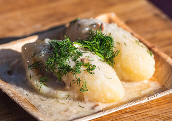 Cepelinai, traditional Lithuanian potato dumplings served with sour cream and garnished with crispy bacon bits and fresh parsley © Michele Ursi