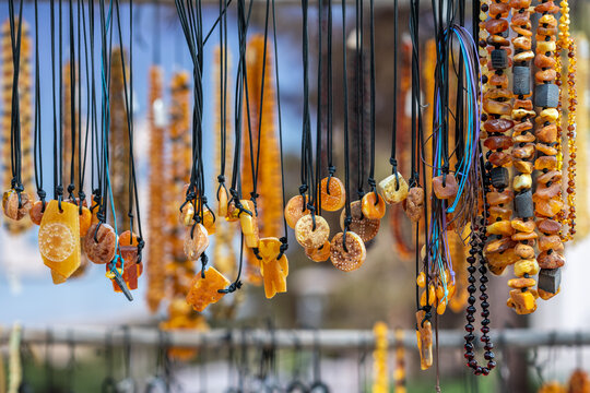Amber necklaces hanging in a stall in a street market. Amber of different colors and sizes. Exposition of stones of amber for tourists, souvenir concept