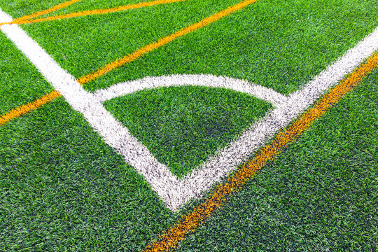 Artificial grass football field with white line corner on the green soccer field.Football field corner with white marks & Race running track treadmill in yellow marksSoccer field marking corner kick