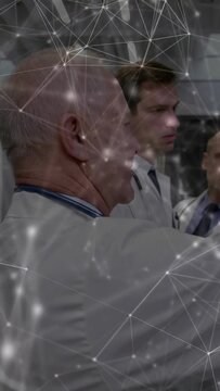 Vertical video: Senior doctor raising arm and speaking, briefing medical team with network overlay