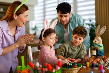 Obraz premium Family enjoying easter activity painting eggs at table