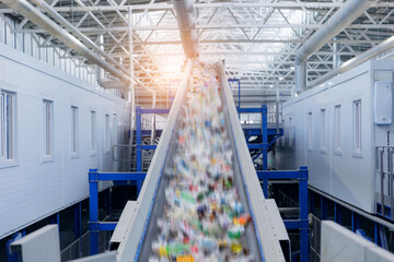 Recycling facility conveyor belt with blurred plastic waste under industrial ceiling sunlight