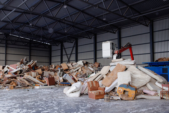 Industrial warehouse filled with large piles or household garbage from chipboard and mattresses of mixed waste and discarded furniture on recycling plant