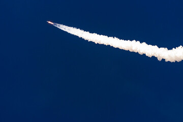 Fototapeta premium Rocket launch with clear blue sky background and contrail of smoke