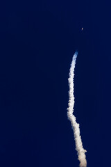 Fototapeta premium Rocket launch with smoke trail against clear blue sky