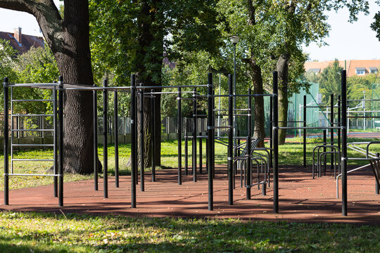 Outdoor fitness station with durable steel pull up bars, parallel bars and complex metal frame construction on rubber safety flooring. Professional street workout sports equipment