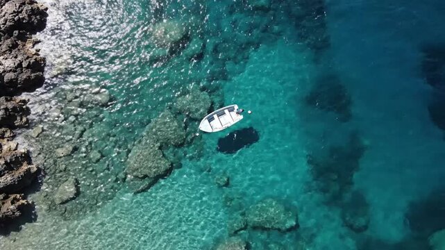 Aerial view of a small white boat near rocky coastline.