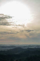 Fototapeta premium Morning sun above layered rainforest hills in Kalimantan