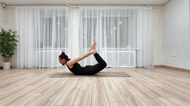 Relaxing Evening Indoor Yoga Practice. Practicing Calming Yoga Sequence With Natural Light At Home. Engaging In Restorative Indoor Yoga Routine Emphasizing Backbends With Plants And Sunlight