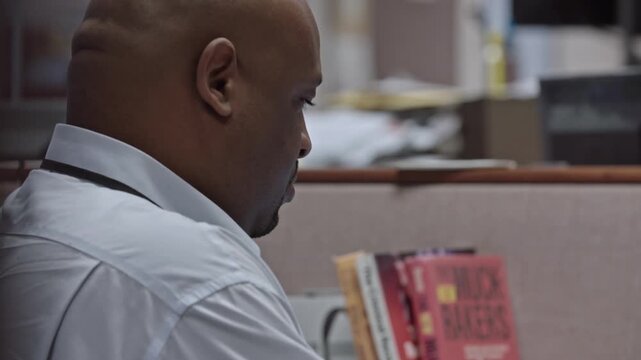 African american prison guard typing on a laptop at his desk inside a female correctional facility