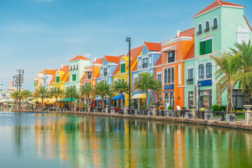 Colorful waterfront buildings with European style architecture and palm trees, Phu Quoc island, Vietnam. Palm trees, cafes and waterfront walkways reflect in water. Coastal tourism district © samael334