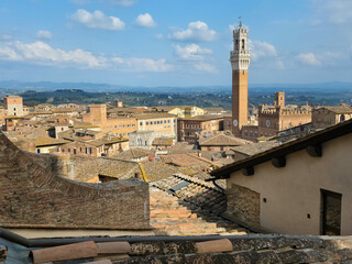 Obraz premium Panoramic Skyline of Siena with Torre del Mangia and Palazzo Pubblico, Italy. High Angle View of Medieval Rooftops in Tuscany under a Cloudy Blue Sky. Historic Italian Cityscape
