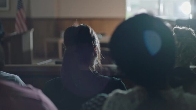 Public spectators sitting in a courtroom during a legal proceeding or trial, awaiting a verdict