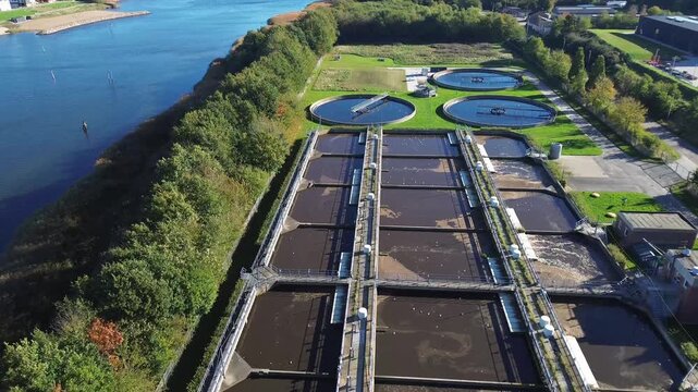 Wastewater treatment facility in Haderslev, Denmark, featuring large rectangular basins and circular clarifiers surrounded by greenery. The plant highlights advanced environmental
