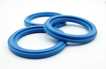 Blue hydraulic seals isolated on white. These rubber rings prevent fluid leakage in mechanical systems. They are crucial components in pumps, cylinders, and valves for machinery.