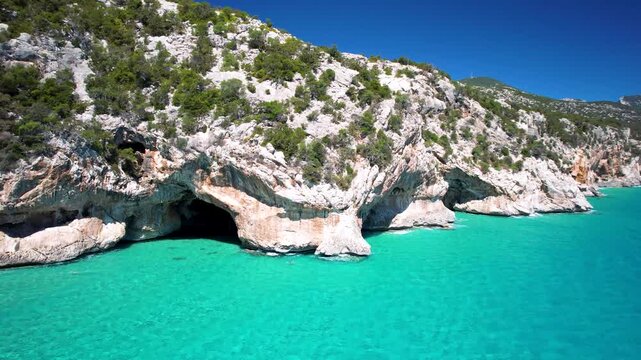 Sardinia Cala Luna sea caves aerial view over turquoise tropical water along white cliffs and coast Golfo di Orosei Italy drone footage 4k cinematic landscape travel destination Mediterranean