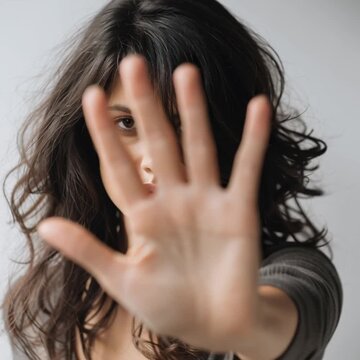 Frau h&auml;lt die Hand vor die Kamera als Stop-Geste. Ausdrucksstarkes Portr&auml;t f&uuml;r Themen wie Grenzen setzen, Nein sagen, Schutz, Selbstbestimmung und pers&ouml;nliche Abgrenzung.